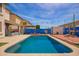 Relaxing backyard oasis featuring a sparkling pool, lounge area, vibrant landscaping and blue accent wall at 3708 S 104Th Ln, Tolleson, AZ 85353
