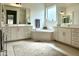 Bright bathroom featuring dual sinks, a soaking tub, and white cabinetry at 7158 E Posada Ave, Mesa, AZ 85212