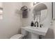 Elegant half bath featuring pedestal sink, round mirror, and modern fixtures at 7822 W Mcrae Way, Glendale, AZ 85308