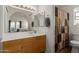 Well-lit bathroom with a large mirror, vanity, and shower with patterned curtain at 7822 W Mcrae Way, Glendale, AZ 85308
