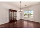 Well-lit dining room featuring wood floors, elegant chandelier, and large windows for natural light and backyard views at 9625 W Prospector Dr, Queen Creek, AZ 85144