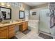 This bathroom offers dual sinks, a tub, and a shower, with natural light streaming through glass block windows at 9653 E Sidewinder Trl, Scottsdale, AZ 85262