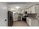 A well-lit kitchen shows white cabinets, stainless steel appliances, gray-toned flooring, and a tile backsplash at 1064 S 97Th St, Mesa, AZ 85208