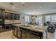 Open kitchen featuring a central island, dark cabinets, tile backsplash, and modern appliances at 1197 W Fir Tree Rd, Queen Creek, AZ 85140