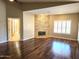 Spacious living room with hardwood floors and a stone fireplace, complemented by bright window shutters at 1348 E Los Arboles Dr, Tempe, AZ 85284