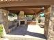 Outdoor kitchen with stone accents offers a cozy fireplace, sink, and ample counter space in a covered patio at 1348 E Los Arboles Dr, Tempe, AZ 85284