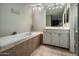 Relaxing bathroom featuring a soaking tub, a large vanity area, and neutral tiling throughout the space at 13631 N Canterbury Dr, Phoenix, AZ 85023