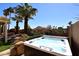 Backyard with a modern hot tub, desert landscaping, and towering palm trees, creating a private oasis at 15061 W Pinchot Ave, Goodyear, AZ 85395