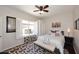 Cozy bedroom with a striped bed, patterned rug, and window with plantation shutters at 15061 W Pinchot Ave, Goodyear, AZ 85395
