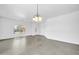 Bright living room with gray tile floor, neutral paint, and chandelier lighting near the front door at 15856 W Calavar Rd, Surprise, AZ 85379