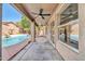 A covered patio with ceiling fans overlooks a refreshing pool and serene backyard at 15856 W Calavar Rd, Surprise, AZ 85379