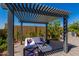 A backyard sitting area under a modern pergola, with an outdoor kitchen and a patio at 17656 W Bajada Rd, Surprise, AZ 85387