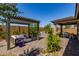 Backyard with a seating area under a modern pergola, an outdoor kitchen, and covered patio at 17656 W Bajada Rd, Surprise, AZ 85387