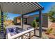 Backyard sitting area underneath a modern pergola with outdoor kitchen and patio at 17656 W Bajada Rd, Surprise, AZ 85387