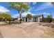Charming home features a driveway with trees and a black fence offering privacy at 1985 S Plaza Dr, Apache Junction, AZ 85120