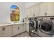 Well-appointed laundry room featuring white cabinets, modern appliances, stylish floors, and a window at 21397 N 78Th St, Scottsdale, AZ 85255