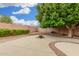 Large backyard with a concrete patio, mature tree, and a brick fire pit at 2143 N Chestnut Cir, Mesa, AZ 85213