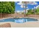 Refreshing backyard pool with rock waterfall feature, surrounded by lush greenery and palm trees at 2143 N Chestnut Cir, Mesa, AZ 85213
