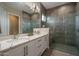 Stylish bathroom with a dual sink vanity, granite countertops, custom cabinets, and a glass-enclosed shower at 26673 W Ponderosa Ln, Buckeye, AZ 85396