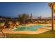 Twilight view of a backyard pool and spa with an outdoor kitchen and desert landscaping at 26673 W Ponderosa Ln, Buckeye, AZ 85396
