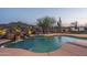 Backyard pool area, featuring a relaxing waterfall with desert plants, rocks, and furniture at 26673 W Ponderosa Ln, Buckeye, AZ 85396