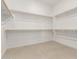 Spacious walk-in closet with wood shelving and rods, and neutral tile flooring at 33857 N Borgata Trl, San Tan Valley, AZ 85144