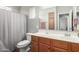 Well-lit bathroom featuring a single sink vanity with wood cabinets and a shower with a curtain at 343 N 169Th Ave, Goodyear, AZ 85338