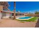 Backyard view shows a pool and screened patio surrounded by grass and desert landscaping under a blue sky at 5421 W Seldon Ln, Glendale, AZ 85302