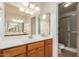 Bathroom with a wood vanity, large mirror, and shower featuring a sliding glass door at 5421 W Seldon Ln, Glendale, AZ 85302