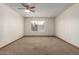 Spacious bedroom with plush carpet, a ceiling fan, and a window overlooking the neighborhood at 5421 W Seldon Ln, Glendale, AZ 85302