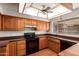Functional kitchen features wood cabinets, black appliances, and a large window above the sink at 5421 W Seldon Ln, Glendale, AZ 85302