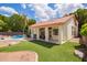 Beautiful backyard with a covered patio, artificial grass and a blue pool surrounded by lush greenery at 5428 W Wethersfield Dr, Glendale, AZ 85304