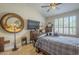 Cozy bedroom featuring a unique mirror, ceiling fan, and natural light from shuttered windows at 5900 W Orchid Ln, Chandler, AZ 85226