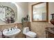 Elegant powder room featuring decorative mirror, pedestal sink, tile wainscoting, and framed artwork at 5900 W Orchid Ln, Chandler, AZ 85226