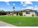Charming single-story home with lush front lawn, complemented by mature landscaping and blue sky at 7502 E Princeton Ave, Scottsdale, AZ 85257