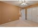 Bedroom features a ceiling fan, carpeting, and closet with an open door to a hallway at 7916 W Mary Ann Dr, Peoria, AZ 85382