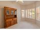 Cozy room featuring carpet flooring, neutral paint, natural light from louvered windows, and a wooden entertainment center at 7916 W Mary Ann Dr, Peoria, AZ 85382