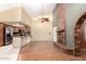 Open-concept layout with a brick fireplace, vaulted ceiling, and view of the kitchen at 9039 E Winchcomb Dr, Scottsdale, AZ 85260