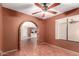 View of the living room featuring hardwood floors, brick archway, ceiling fan, and bright natural lighting at 9039 E Winchcomb Dr, Scottsdale, AZ 85260