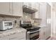 Close-up of kitchen with granite countertops, stainless steel range and gray cabinetry at 907 N Mountain Rd, Mesa, AZ 85207