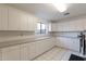 Bright laundry room with ample storage, white cabinets, and tiled flooring at 1234 E Claire Dr, Phoenix, AZ 85022