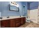 A stylish bathroom with a double sink vanity, toilet, and shower-tub combination in a blue-themed space at 13155 W Monterey Way, Litchfield Park, AZ 85340
