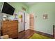 Bedroom with green walls, hard floors, dresser, open closet, and neutral earth-tone color palette at 13155 W Monterey Way, Litchfield Park, AZ 85340