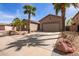 Well-maintained home featuring desert landscaping, a two-car garage and mature palm trees at 13155 W Monterey Way, Litchfield Park, AZ 85340