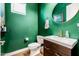 Modern bathroom with an elegant circular mirror, dark wood vanity, and green accent wall at 1341 E Paseo Way, Phoenix, AZ 85042