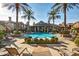 Resort-style pool area with luxurious lounge chairs, lush palm trees, and a clubhouse in the background at 14250 W Wigwam Blvd # 2111, Litchfield Park, AZ 85340