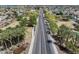 Aerial shot of a long road lined with lush palm trees, homes, and greenery at 14554 W Evans Dr, Surprise, AZ 85379