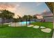 Backyard featuring a pool with a safety fence, artificial turf, mature landscaping and stepping stones at 14554 W Evans Dr, Surprise, AZ 85379