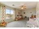 Bright bedroom features a ceiling fan, playful decor, and a large window with neighborhood views at 14554 W Evans Dr, Surprise, AZ 85379