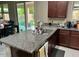 Kitchen island featuring granite countertops, dark wood cabinets, and stainless steel sink at 16810 W Portland St, Goodyear, AZ 85338